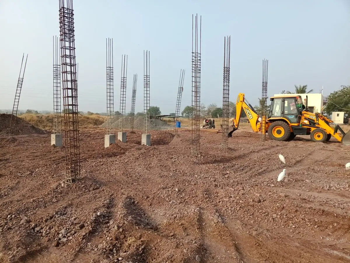 Reinforced concrete columns rising for the control room, with a backhoe loader on site