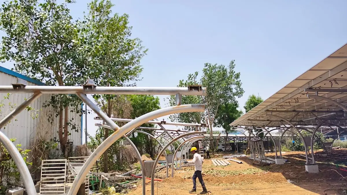 Curved steel carport frames beside a completed solar canopy at the Suzuki plant, Gurugram