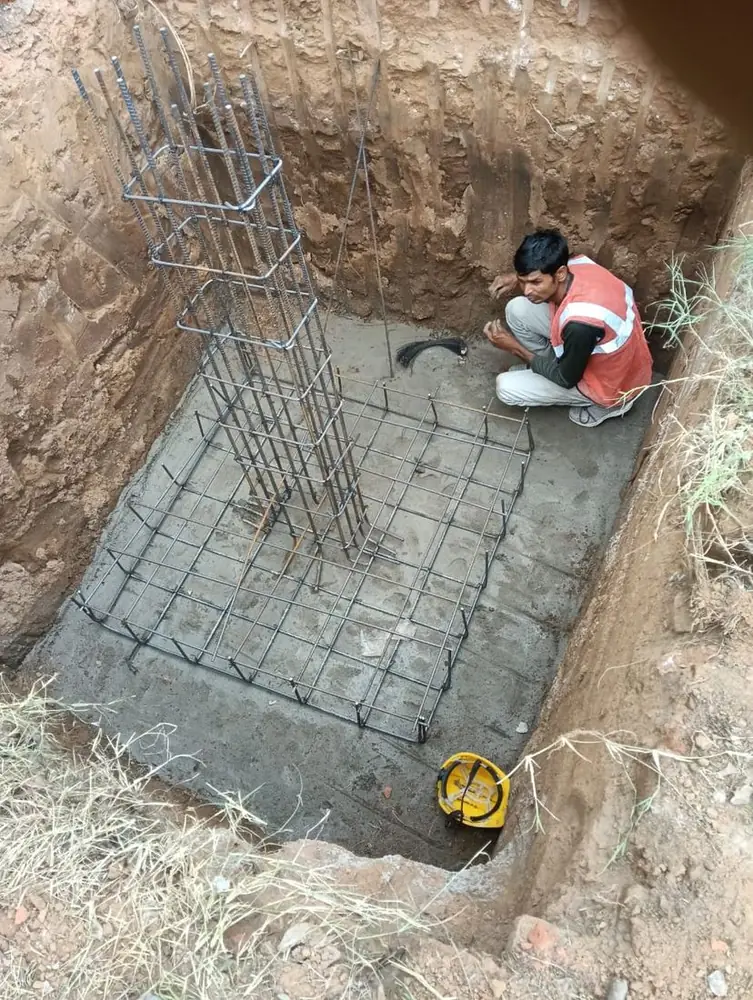Worker placing reinforcement for a carport column footing